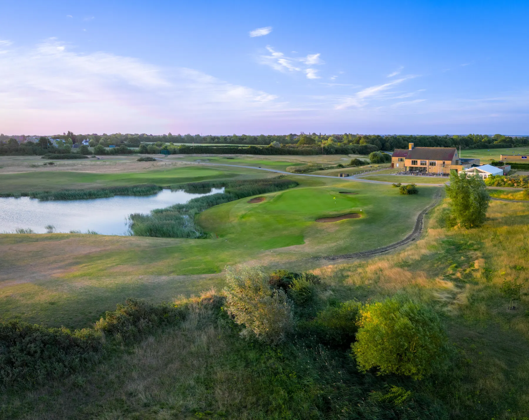 The clubhouse above a green and lake, early morning