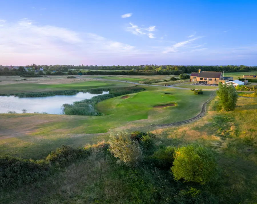 The clubhouse above a green and a lake, early morning