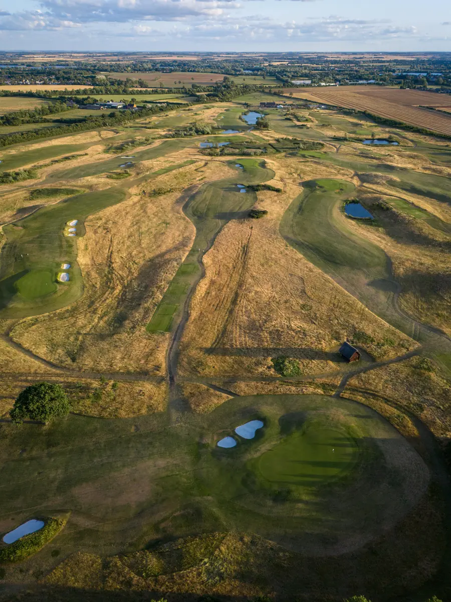 Links fairways and golden rough from the air, lakes beyond
