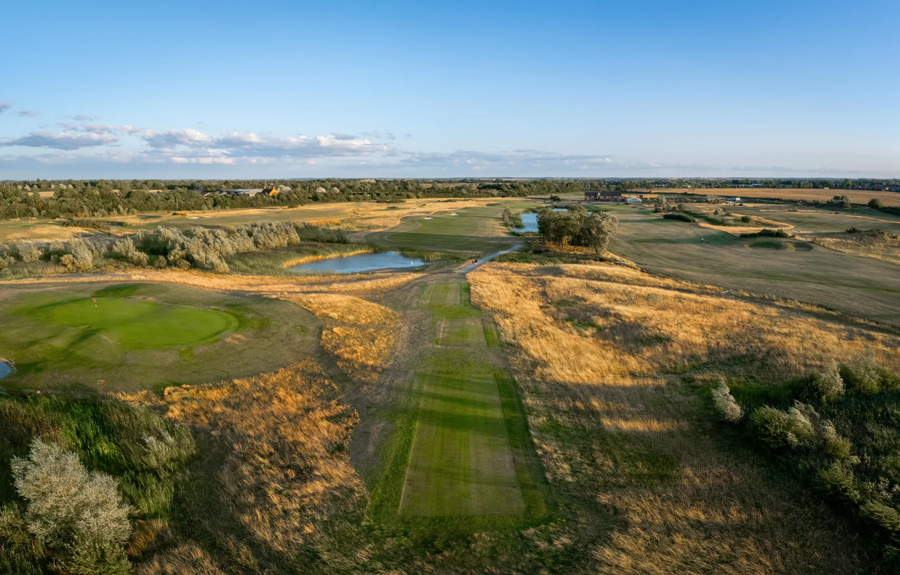 A fairway running to the clubhouse through golden rough, from the air