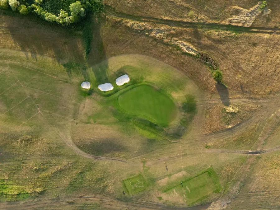 A green and its pot bunkers in the rough, straight down from height