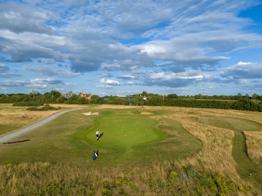 Golfers on a green under a big summer sky