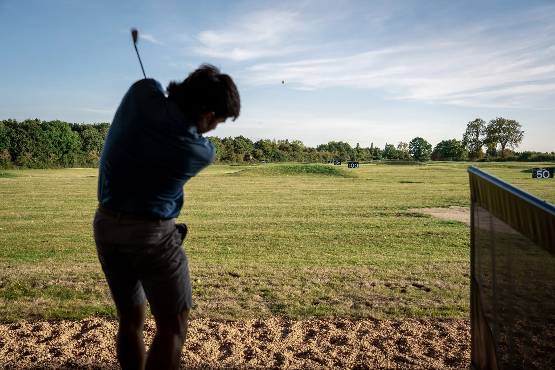A golfer at the top of the backswing on the range, in silhouette
